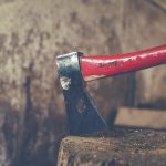 Un hacha roja clavada en un tronco de madera