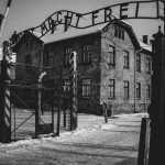 Imagen de la entrada al campo de concentración de Auschwitz en blanco y negro con la inscripción 'Arbeit macht frei'