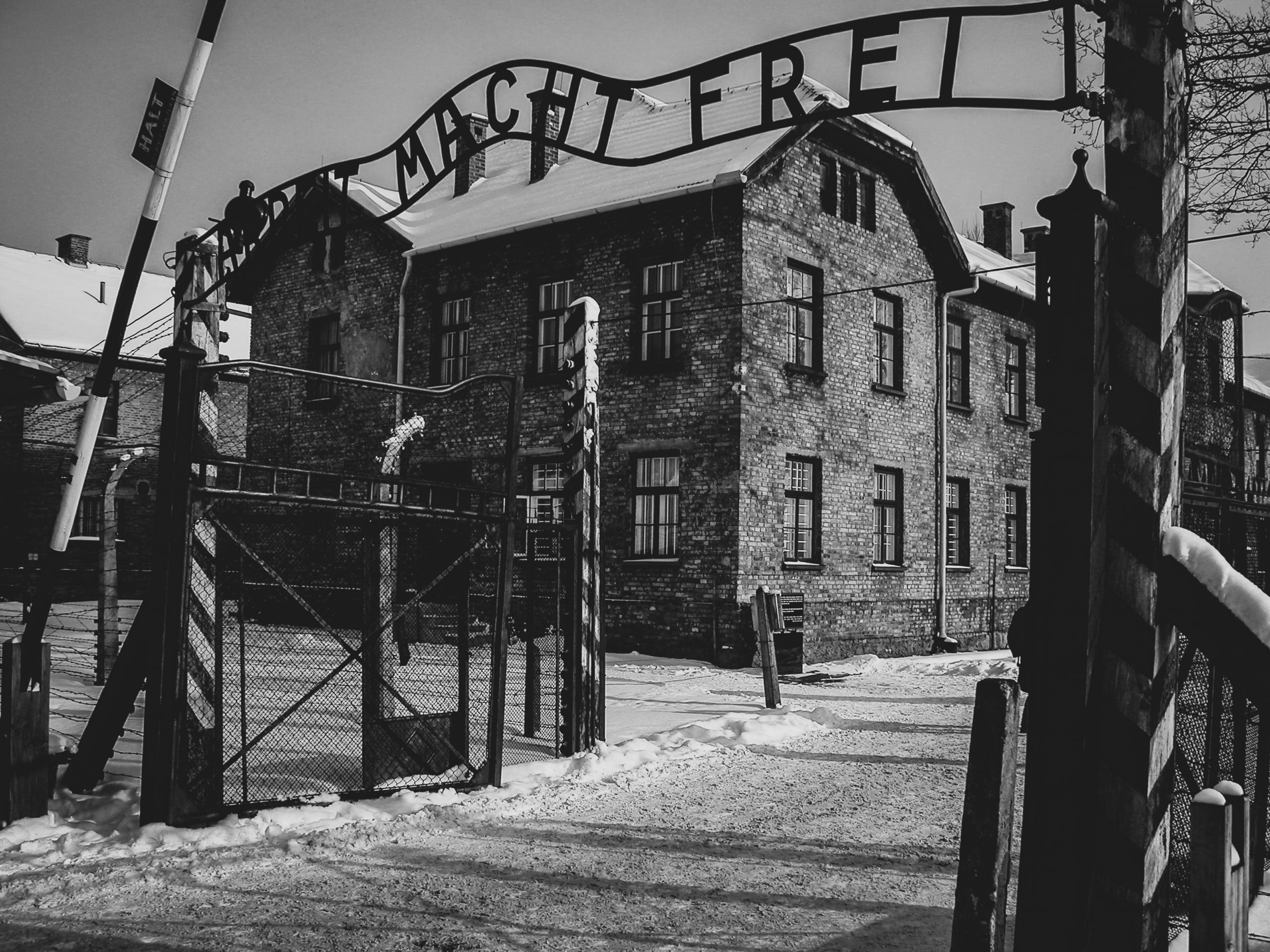 Imagen de la entrada al campo de concentración de Auschwitz en blanco y negro con la inscripción 'Arbeit macht frei'